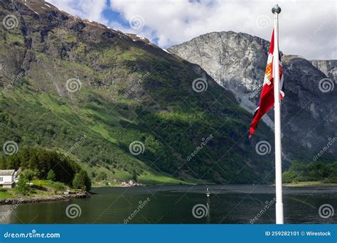 Norwegian Flag Against A Landscape In Narrow Fjord In Aurland In