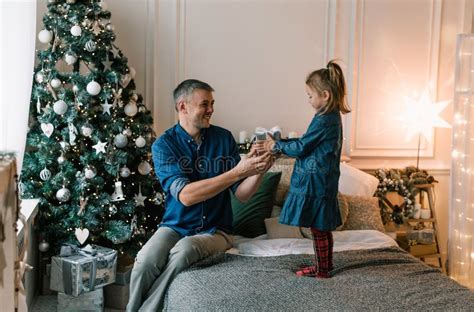 Um Pai Cuidador D Um Presente De Natal Para Sua Filha Pequena Sentada