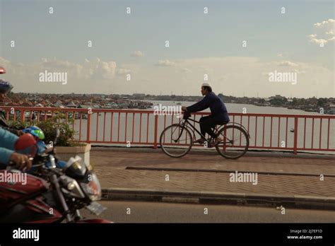 A Man Riding Bicycle On Ampera Bridge Across River Musi In Palembang