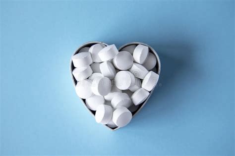 White Round Heart Shaped Tablets On A Blue Background Stock Photo