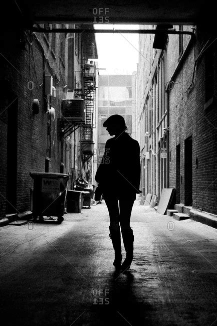 Silhouette of woman walking in city alley stock photo - OFFSET