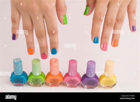 fingers with different colors nail polish bottles Stock Photo - Alamy