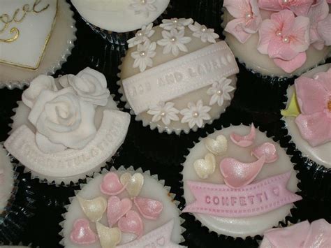 Cupcakes Decorated With White And Pink Frosting Are Arranged On A Black