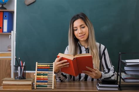 Professora Jovem Sentada Na Mesa Da Escola Na Frente Do Quadro Negro Na