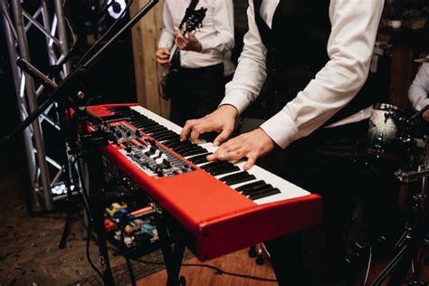 Premium Photo | Closeup of hands playing a red piano synthesizer in a cover band