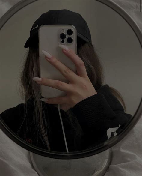 A Woman Taking A Selfie In Front Of A Round Mirror With Her Cell Phone