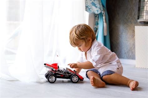 Niño pequeño está sentado en el suelo de la casa y jugando con una