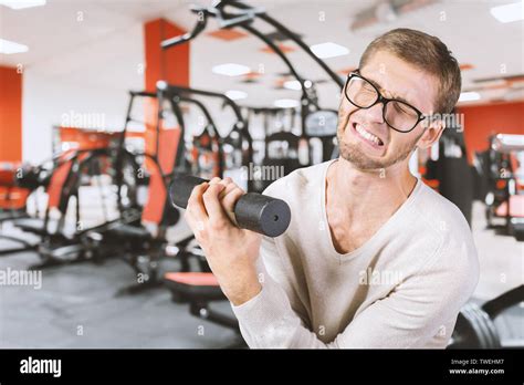 Funny weak man tries to lift a weight Stock Photo - Alamy