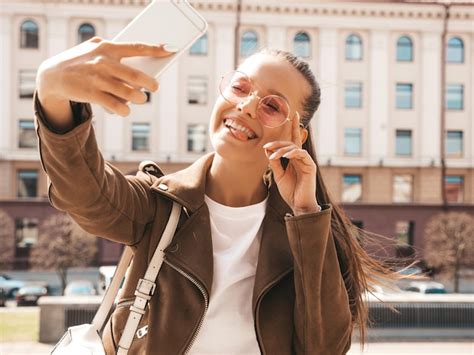 여름 Hipster 재킷에 아름 다운 웃는 갈색 머리 소녀 스마트 폰에서 모델 촬영 Selfie입니다 무료 사진