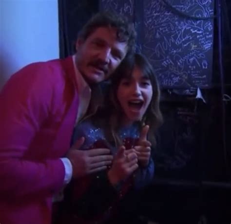 A Man And Woman Standing Next To Each Other In Front Of A Chalkboard Wall