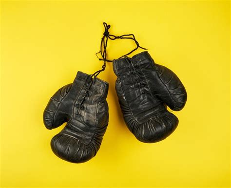 Premium Photo | Pair of black leather very old boxing gloves on a yellow background