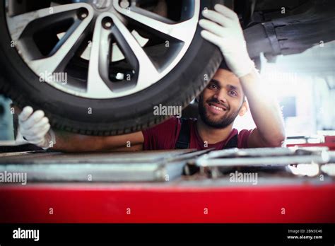 Portrait Confident Smiling Male Mechanic Working Under Car In Auto