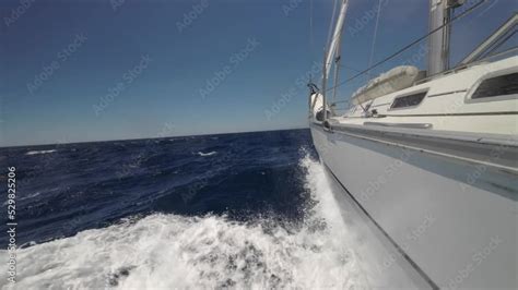 Floating Sailing Yacht With Spread Sails Splitting The Sea Waves And An