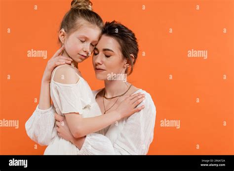 Motherly Love Mother And Daughter Hugging Each Other On Orange Background Closed Eyes White