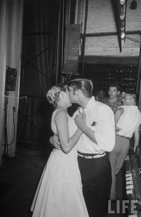 A Man And Woman Kissing While Standing Next To Each Other In Front Of A Piano