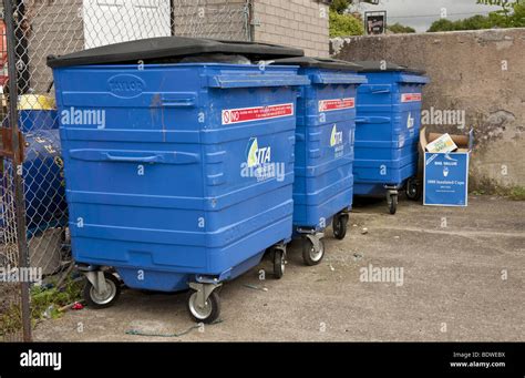 Three Large Blue Plastic Commercial Wheelie Bins Full Of Rubbish Stock