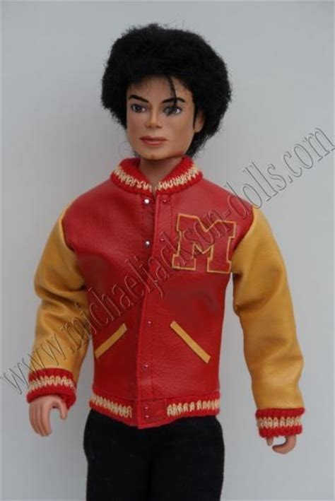 The Doll Is Wearing A Red Jacket And Black Pants With Gold Trims On It