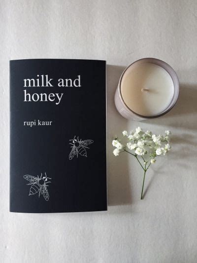 A Book Next To A Candle And Some Flowers On A White Surface With The