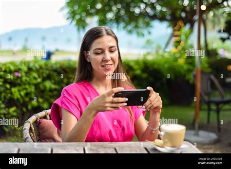 Beautiful Brunette Woman Sitting By The Table And Taking Photo Of Her Cappuccino Stock Photo Alamy