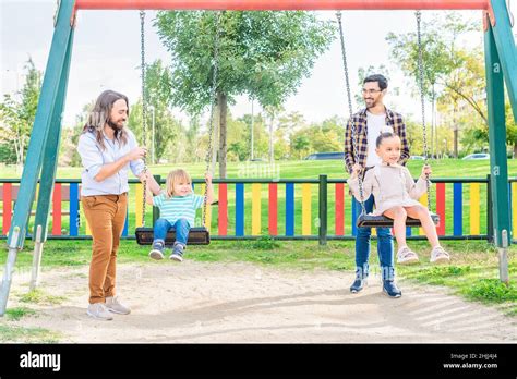 Una pareja gay jugando con sus hijos en el columpio Fotografía de stock Alamy