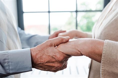 Vista Recortada De Pareja De Ancianos Cogidos De La Mano En Casa Foto