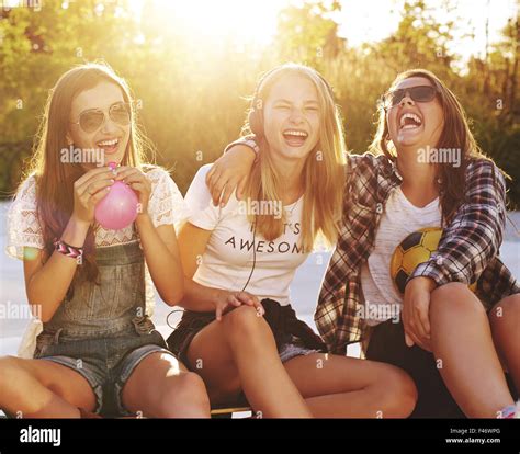 Group Of Girls Laughing While Sitting Outside Enjoying The Summer Stock