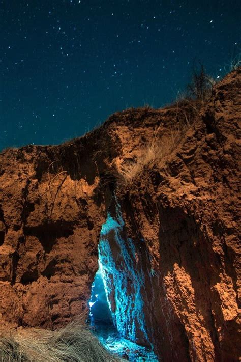 The Night Sky Is Filled With Stars Above A Rocky Cliff And Water Stream