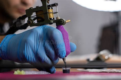 Tattoo Artist Dipping The Needle Of A Tattoo Machine Into The Ink Stock