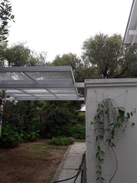 An Outdoor Area With A White Building And Green Plants