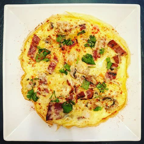 A White Plate Topped With An Omelet Covered In Toppings