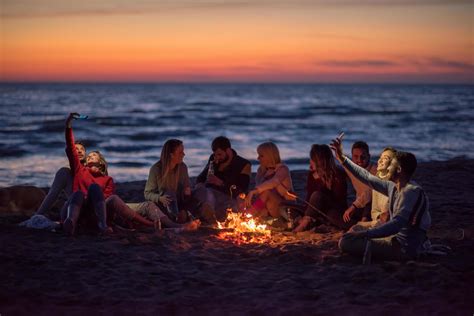 A Group Of Friends Enjoying Bonfire On Beach Stock Photo At