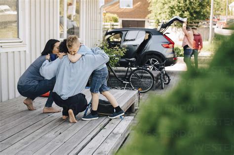 Mothers Embracing Son While Gay Couple Standing By Car During Weekend Stock Photo
