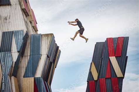 Man Jumping Over A Gap Between Two Buildings Stock Photo And Royalty