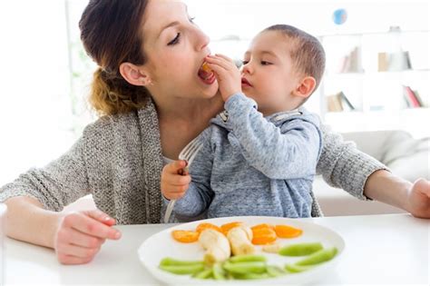 Premium Photo Beautiful Young Mother And Her Son Eating Fruits At Home