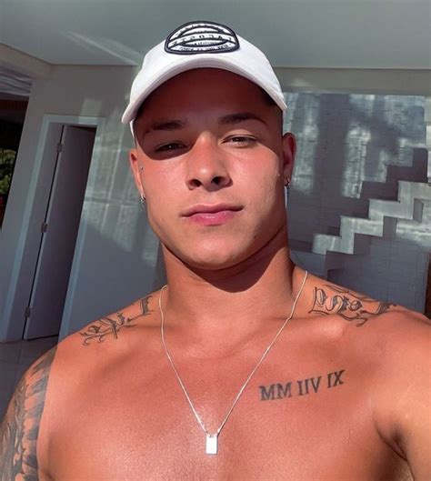 A Shirtless Man With Tattoos On His Chest Wearing A White Hat And No Shirt