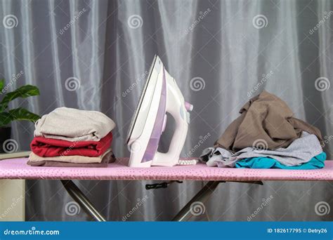 A Man Strokes Linen With An Electric Iron On An Ironing Board