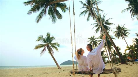 Loving Couple On The Swing On Tropical Beach Woman And Man In White