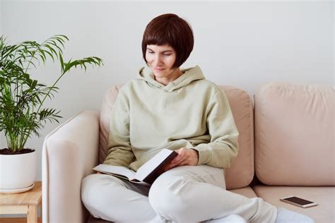 Premium Photo Mature Woman Reading Book Sitting On Sofa Thinking Alone Digital Detox Concept