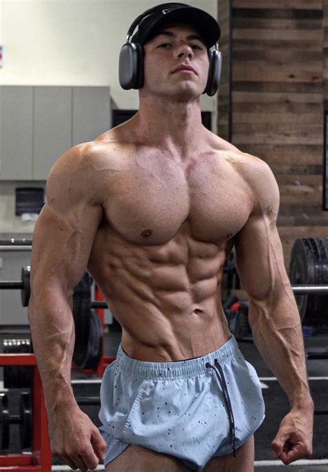 A Shirtless Man With Headphones Standing In A Gym