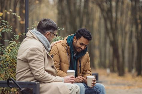 Amigos Un Anciano Y Un Joven Se Sientan En El Parque En Un Banco Y