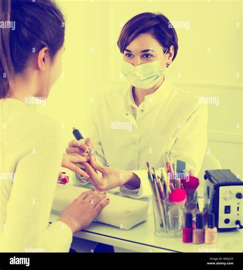 Positive Adult Woman Doing Manicure In Shellac Technique In Nail Salon