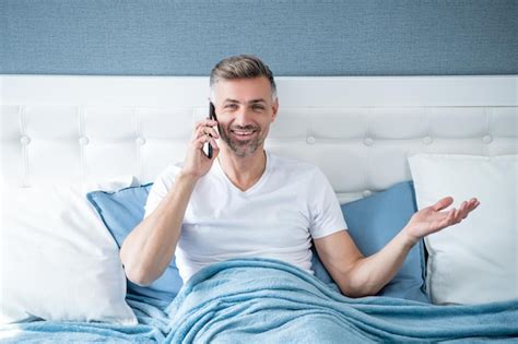 Premium Photo Glad Mature Man In Bed Speaking On Phone