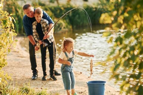 Chica Poniendo Pescado En El Balde Padre Con Hijo E Hija Pescando