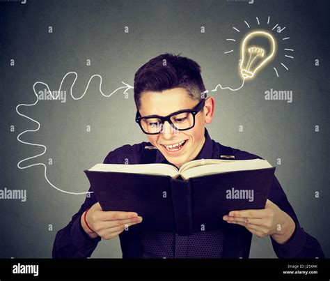 Amazed Happy Young Man In Glasses Reading Book Comes Up With An Idea