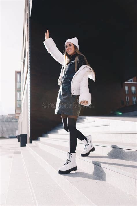 Long Haired Blonde Wearing A White Woollen Cap A White Jacket With A Curvaceous Black Leather