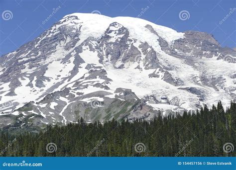 Summit Of Mt Rainier Rises Above Conifer Forested Hills Stock Photo