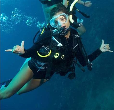 Two People In Scuba Gear Are Posing For The Camera While Holding Their