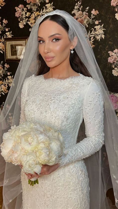 A Woman In A White Wedding Dress Holding A Bouquet Of Flowers And