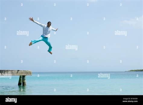 Hispanic man jumping off dock Stock Photo - Alamy