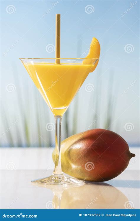 A Martini Glass With Mango Juice A Straw And An Apricot Slice Next To A Fresh Looking Mango